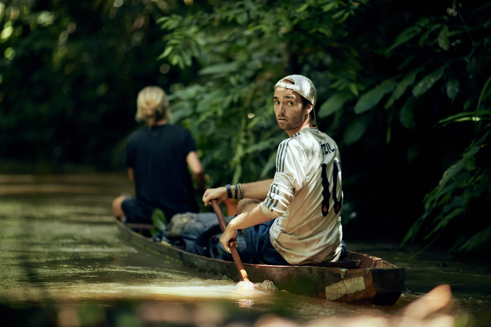 Brian Griffiths paddling a canoe on an Amazonian river, surrounded by forest.